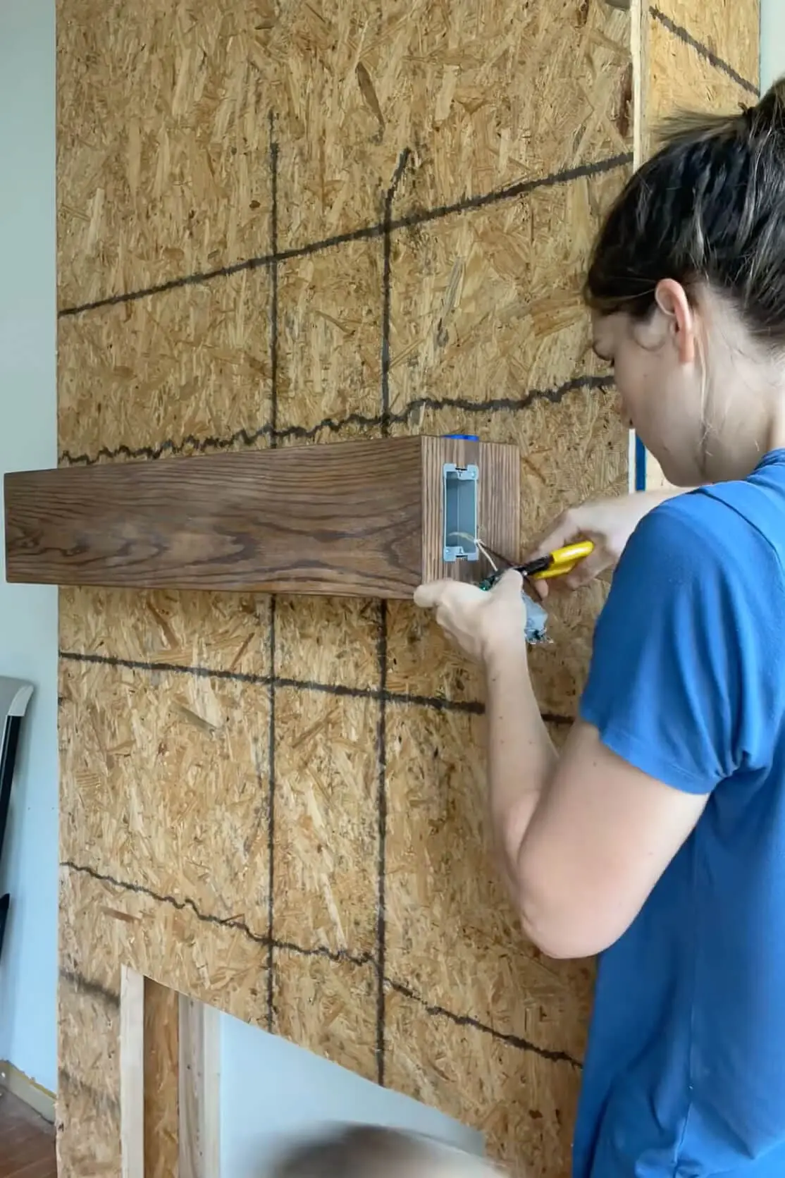 Wiring an electrical outlet inside a DIY fireplace mantel for added functionality.